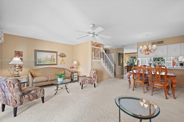 living area with a textured ceiling, ceiling fan with notable chandelier, carpet floors, visible vents, and stairway