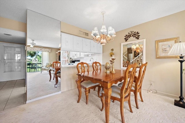 dining space featuring light carpet, visible vents, light tile patterned flooring, a textured ceiling, and ceiling fan with notable chandelier