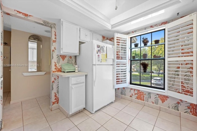 kitchen with light countertops, a raised ceiling, freestanding refrigerator, and white cabinetry