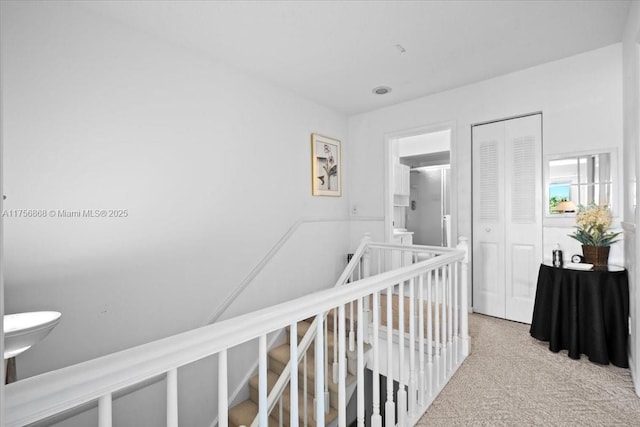 corridor with carpet floors and an upstairs landing