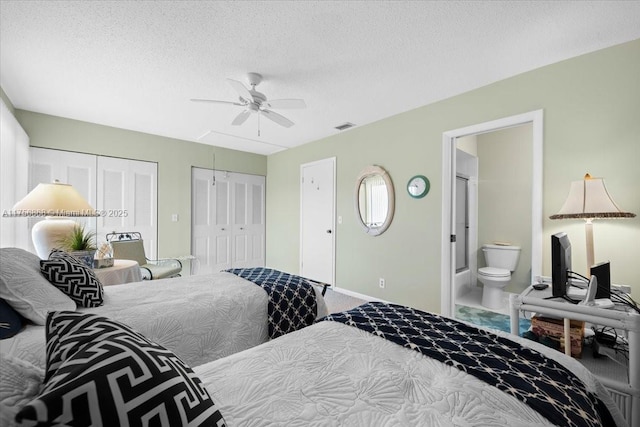 bedroom featuring attic access, visible vents, connected bathroom, a textured ceiling, and two closets