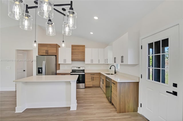 kitchen featuring stainless steel appliances, light countertops, vaulted ceiling, ventilation hood, and light wood-type flooring