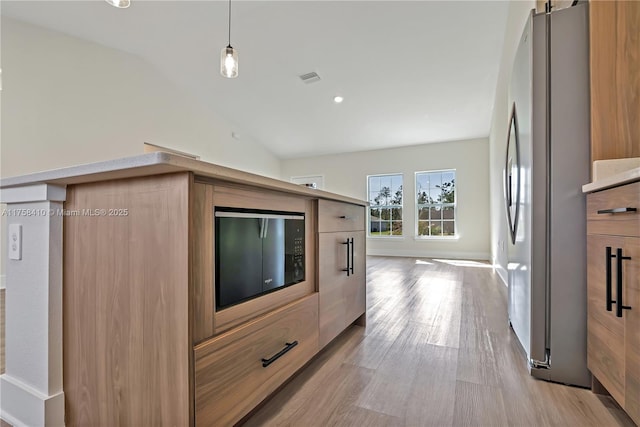 kitchen featuring visible vents, modern cabinets, freestanding refrigerator, vaulted ceiling, and light wood-style floors