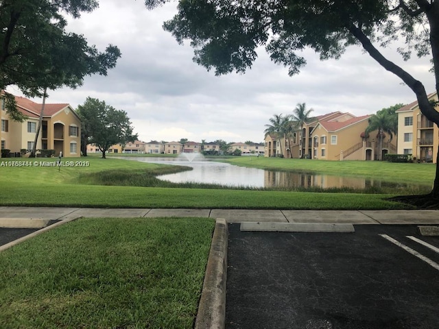 view of property's community with uncovered parking, a residential view, a water view, and a yard