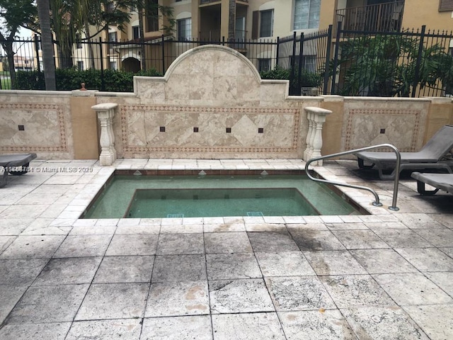 view of pool with fence, a community hot tub, and a patio