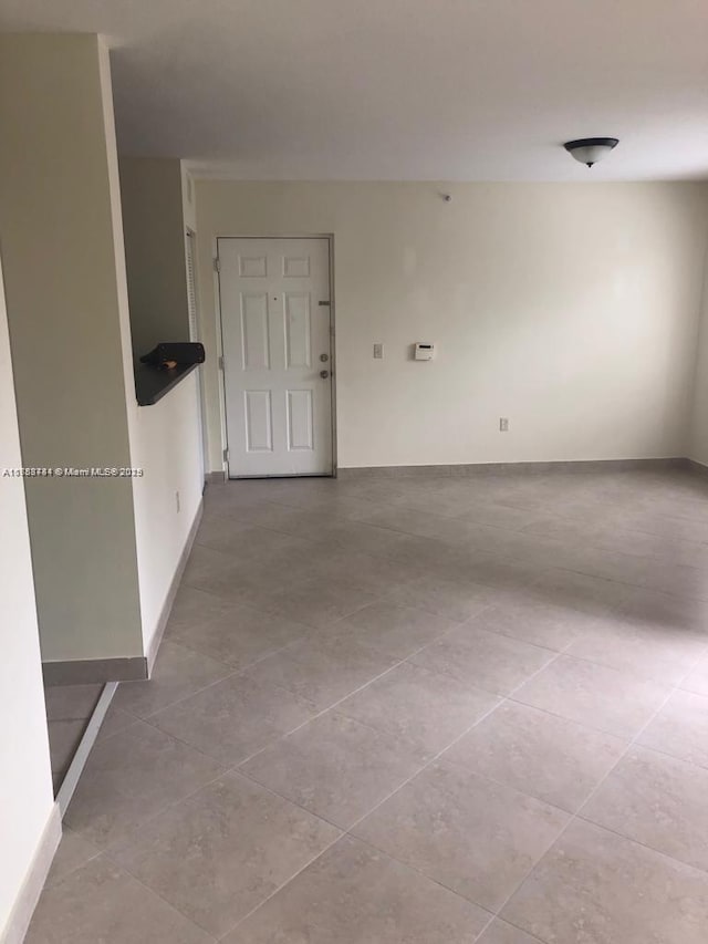 tiled spare room featuring baseboards