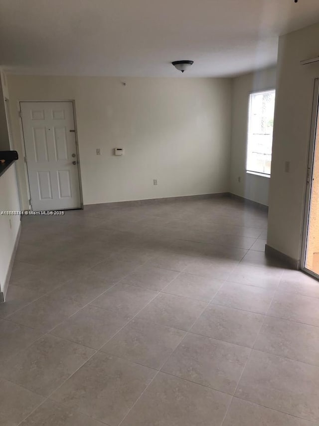 unfurnished room with baseboards and tile patterned floors