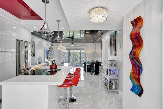 kitchen featuring black electric cooktop, white cabinets, marble finish floor, freestanding refrigerator, and modern cabinets