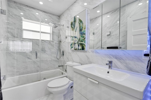 bathroom featuring enclosed tub / shower combo, vanity, toilet, and tile walls