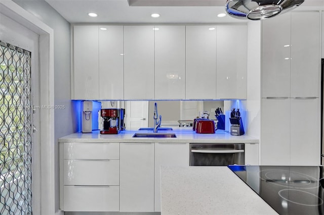 kitchen with a sink, white cabinets, light countertops, dishwasher, and modern cabinets