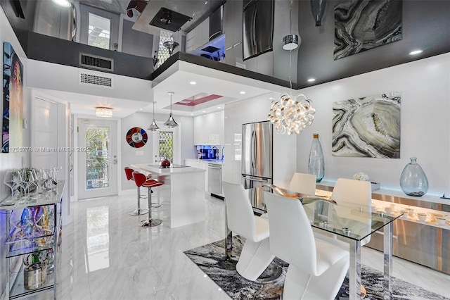 dining room with marble finish floor, visible vents, and a towering ceiling