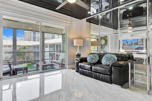 living room with ceiling fan, marble finish floor, a towering ceiling, and baseboards