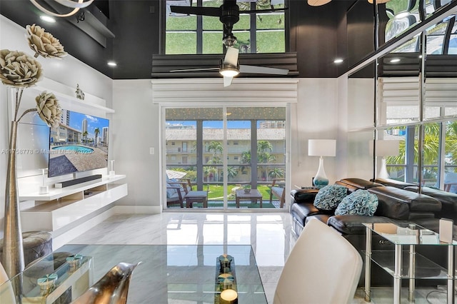 living area featuring marble finish floor, a high ceiling, and baseboards