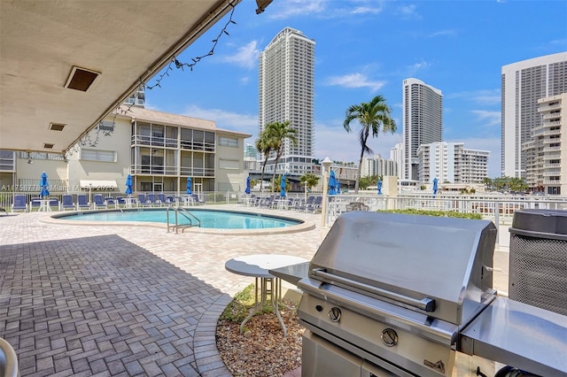 pool with a patio area, a view of city, area for grilling, and fence