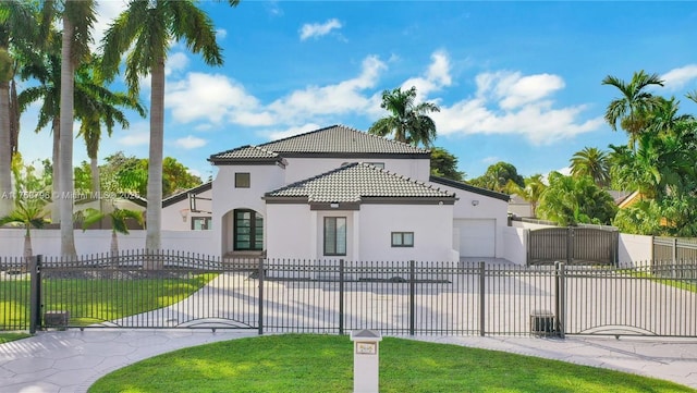 mediterranean / spanish-style house with a fenced front yard, a tile roof, a gate, stucco siding, and a front lawn