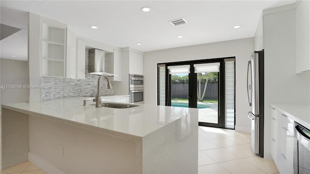 kitchen with stainless steel appliances, a sink, visible vents, wall chimney exhaust hood, and modern cabinets