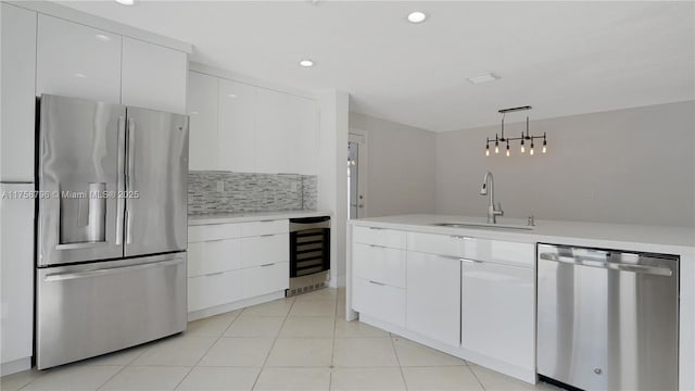 kitchen with tasteful backsplash, beverage cooler, appliances with stainless steel finishes, light countertops, and a sink