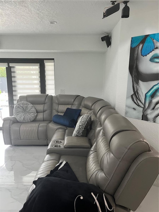 living area with a textured ceiling and marble finish floor