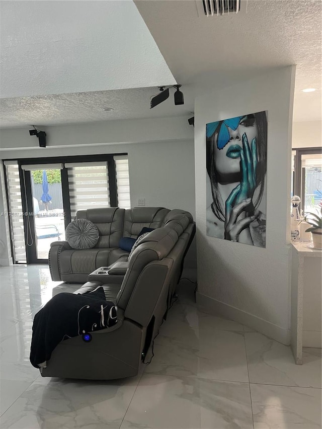 living area featuring a healthy amount of sunlight, visible vents, a textured ceiling, and marble finish floor