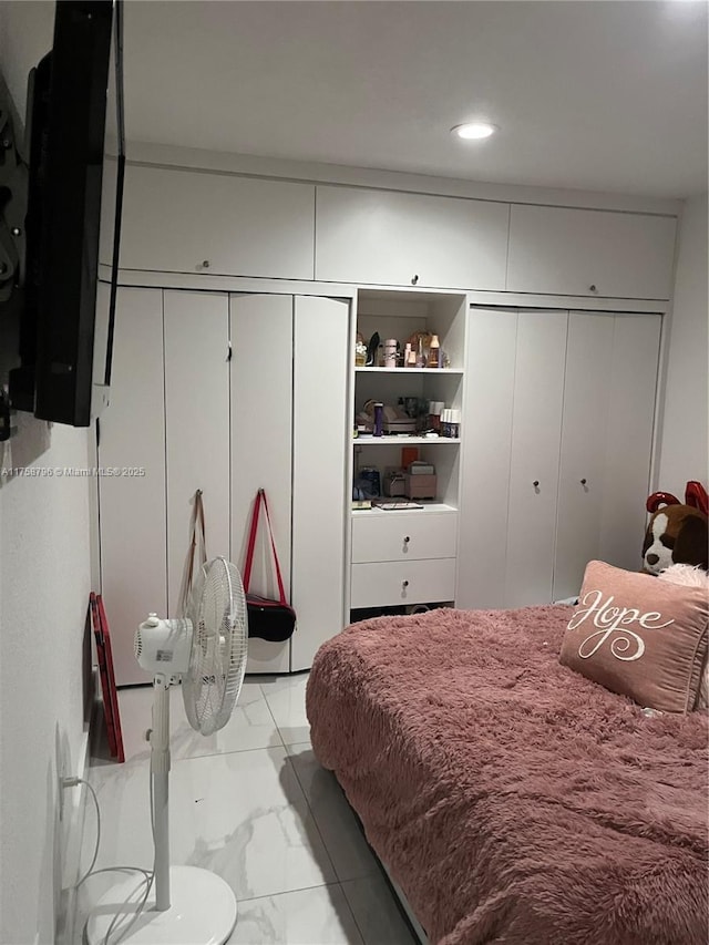 bedroom featuring multiple closets and marble finish floor