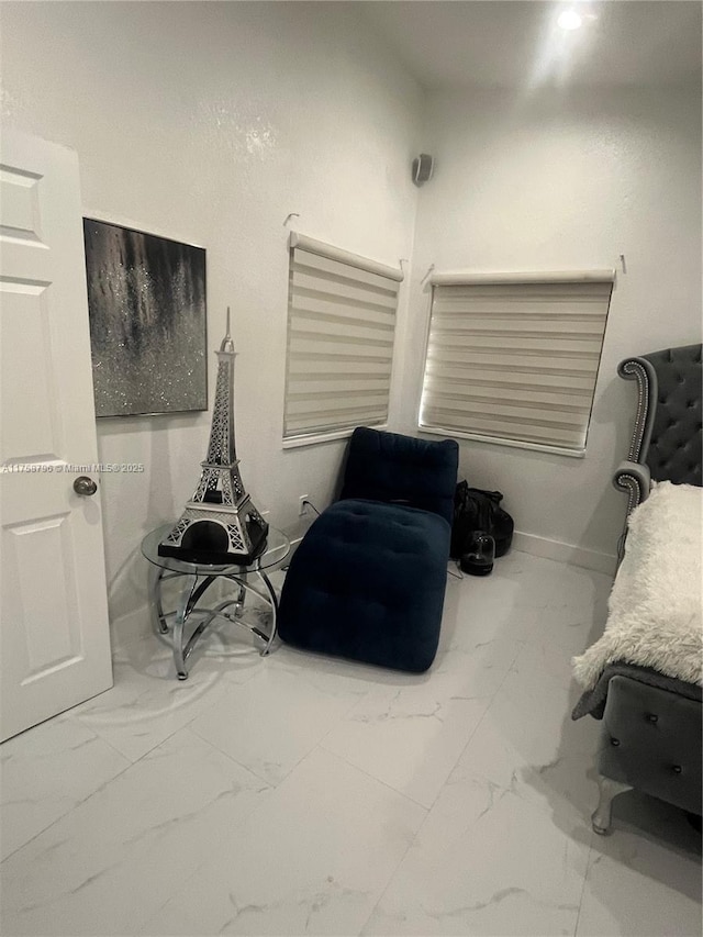 sitting room with marble finish floor and baseboards