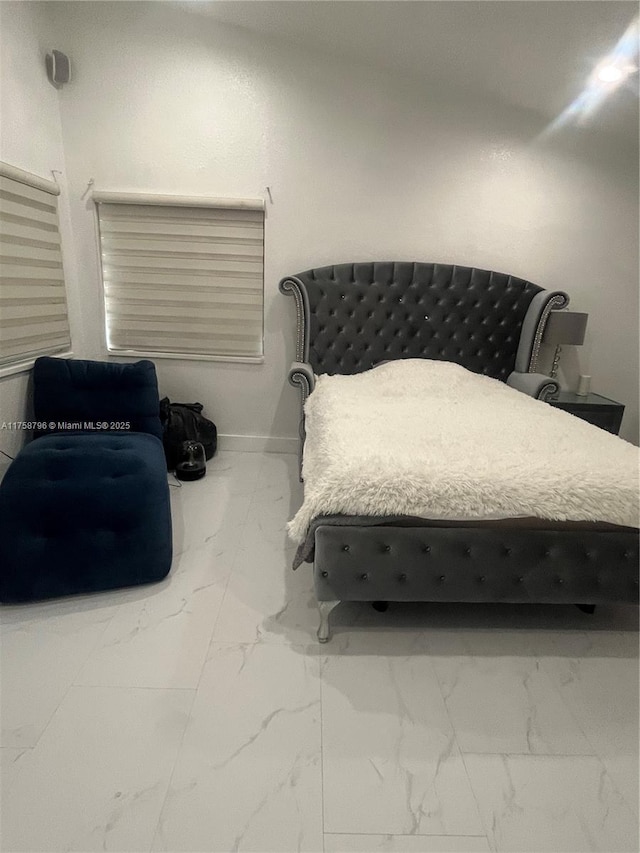 bedroom featuring marble finish floor and baseboards