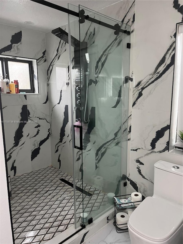 bathroom featuring toilet, marble finish floor, a marble finish shower, and a textured ceiling