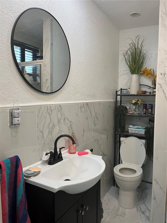 bathroom with a textured wall, marble finish floor, a textured ceiling, and vanity