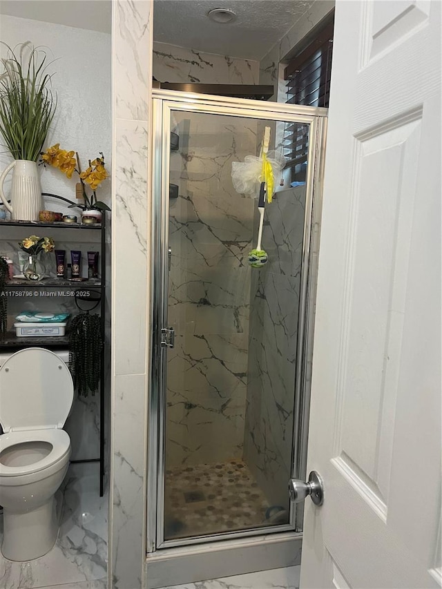 bathroom with toilet, marble finish floor, and a marble finish shower