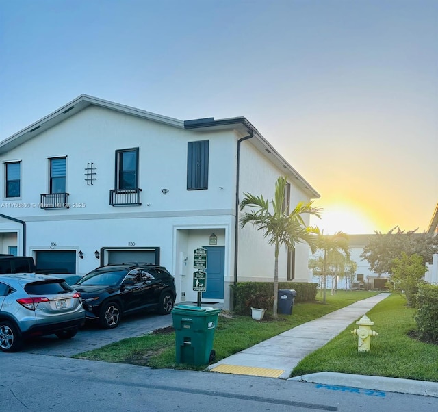 view of front of property with an attached garage, stucco siding, driveway, and a yard