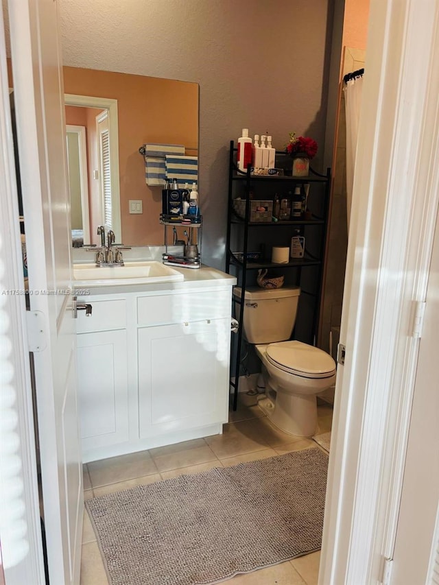 bathroom with toilet, vanity, a textured ceiling, and tile patterned floors