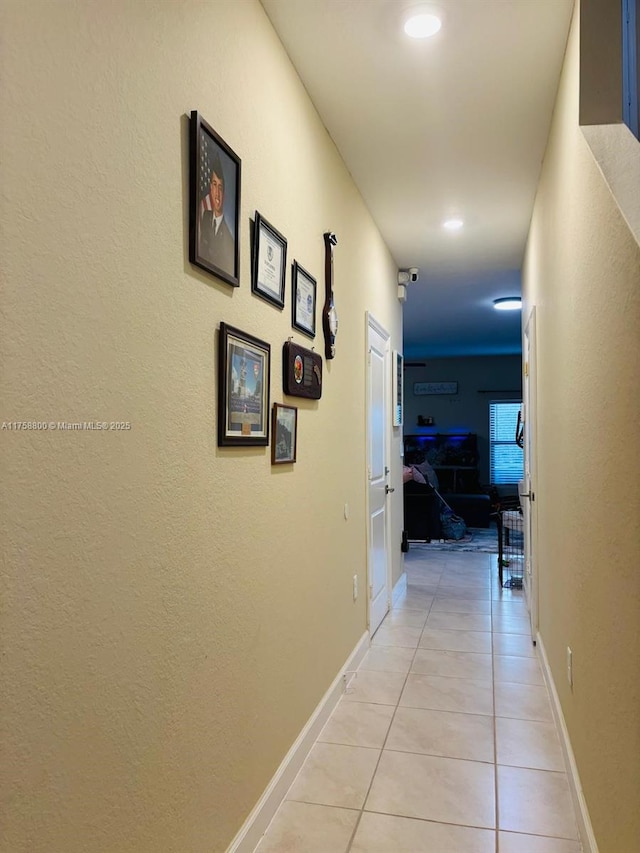 corridor with light tile patterned flooring and baseboards