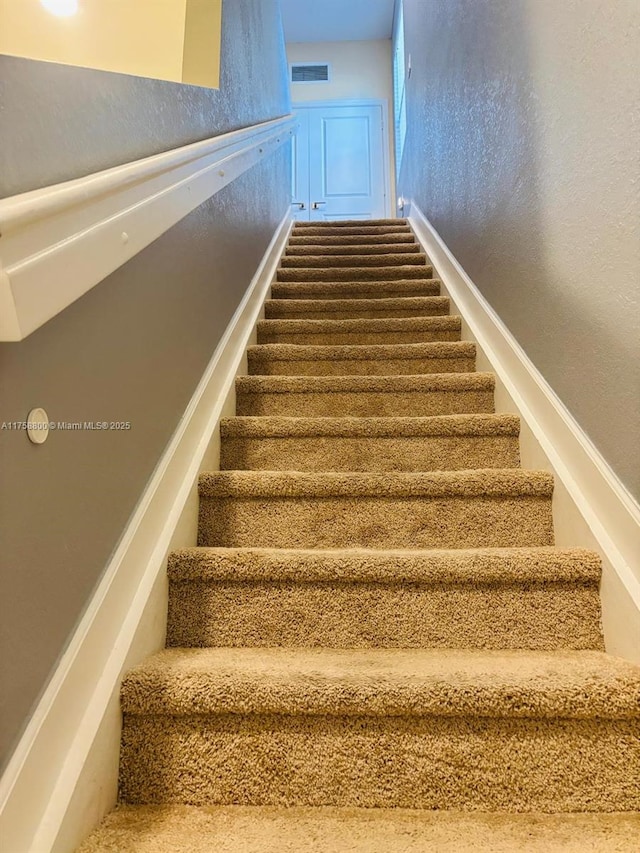 staircase with visible vents and a textured wall