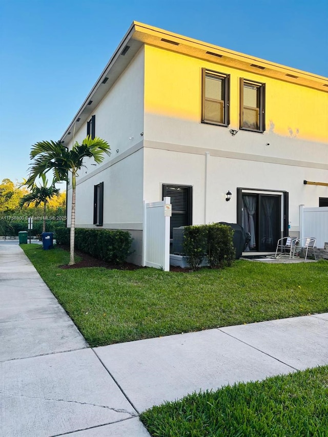 view of side of home with a lawn and stucco siding