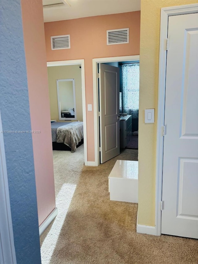 hall featuring baseboards, visible vents, and carpet flooring