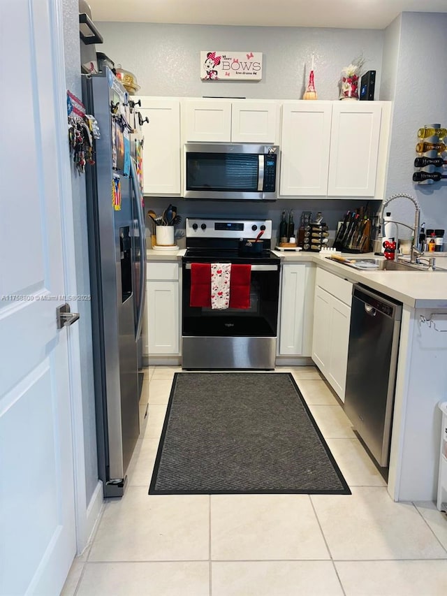 kitchen featuring stainless steel appliances, light countertops, a textured wall, white cabinetry, and a sink