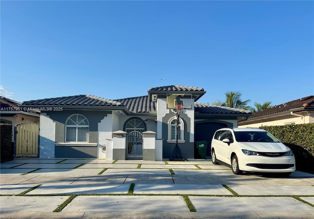 mediterranean / spanish home with a gate, stucco siding, driveway, and a tile roof