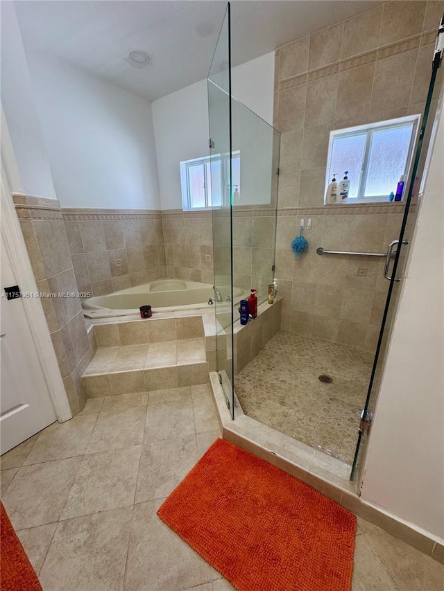 bathroom with a stall shower, a bath, and tile patterned flooring