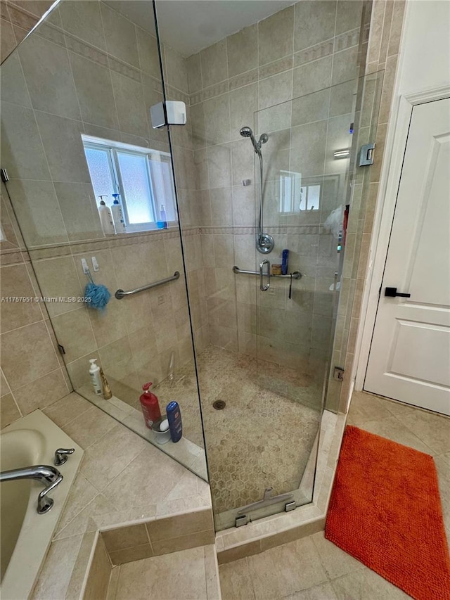 bathroom featuring a stall shower, tile patterned flooring, and a tub to relax in