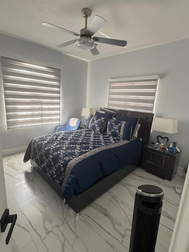 bedroom with baseboards, marble finish floor, a textured ceiling, and ceiling fan