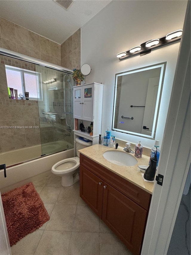bathroom with bath / shower combo with glass door, tile patterned floors, vanity, and toilet