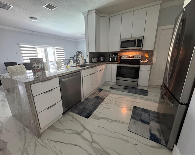 kitchen with appliances with stainless steel finishes, ornamental molding, a peninsula, backsplash, and light marble finish floors