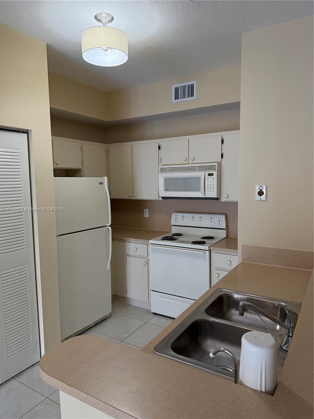 kitchen with white appliances, visible vents, a sink, and light tile patterned floors