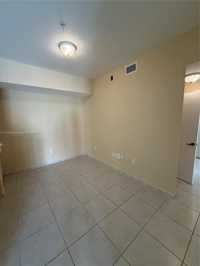 spare room with a textured ceiling, light tile patterned flooring, and visible vents