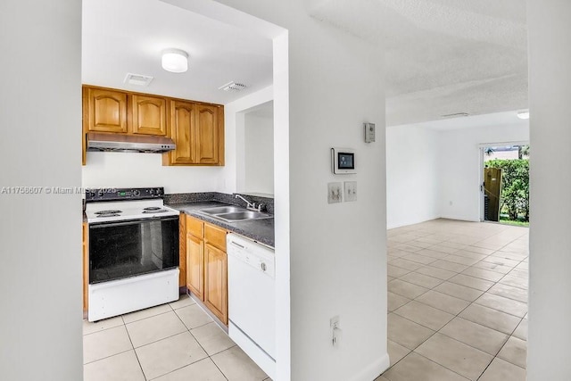 kitchen with light tile patterned floors, under cabinet range hood, white appliances, a sink, and visible vents