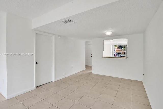 unfurnished room with light tile patterned floors, visible vents, and a textured ceiling