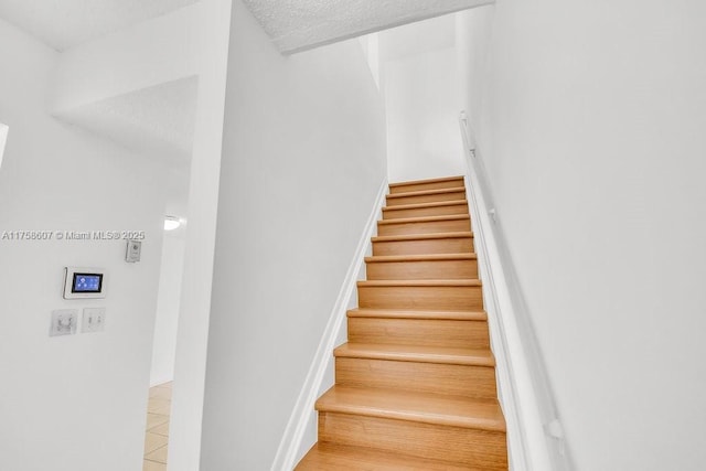 staircase featuring a textured ceiling