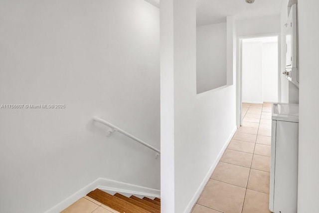 hallway featuring stairs, baseboards, and light tile patterned flooring