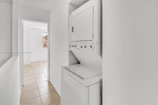 laundry area featuring light tile patterned floors, laundry area, and stacked washer / dryer