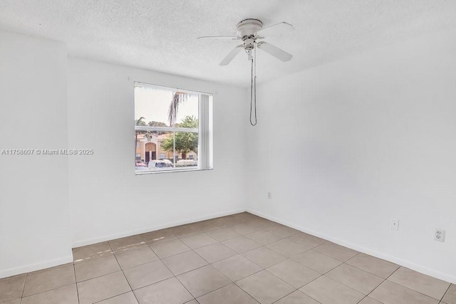 tiled spare room featuring ceiling fan, a textured ceiling, and baseboards